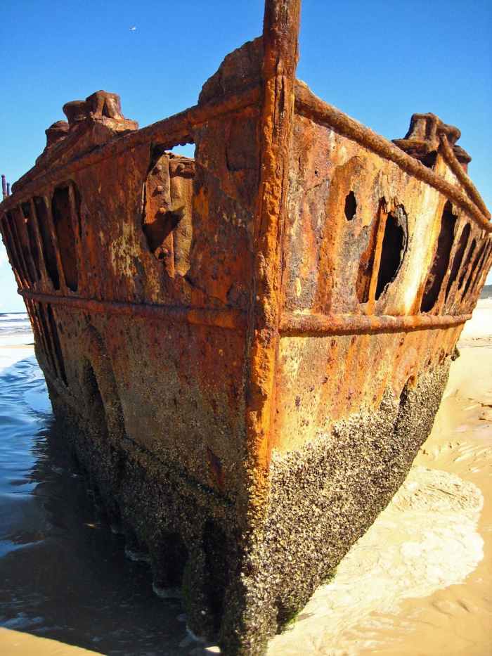 brown metal shipwreck on seashore during daytime